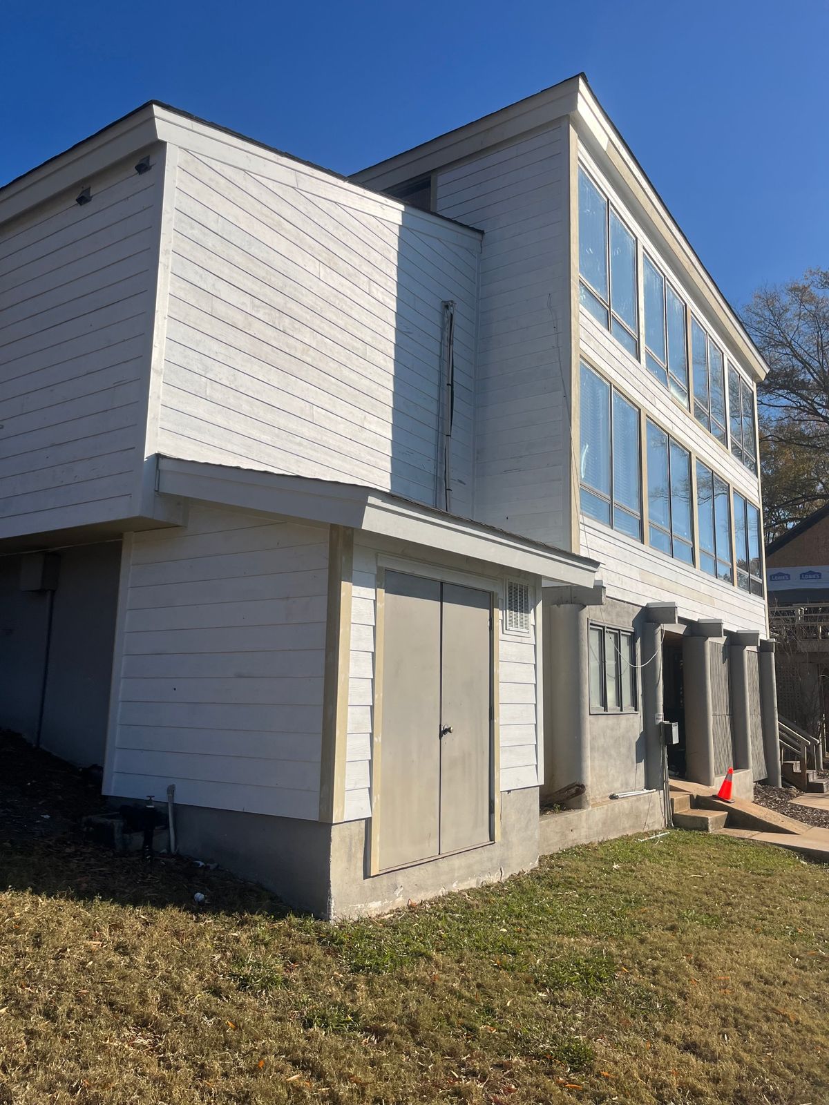 Finished three-story home with new white lap siding and tall window walls